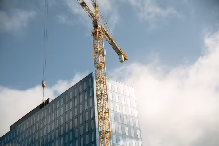 Bilde av en byggkran og et høyhus