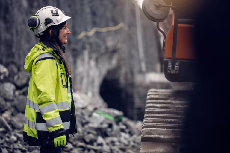 En smilende kvinne på en byggeplass.