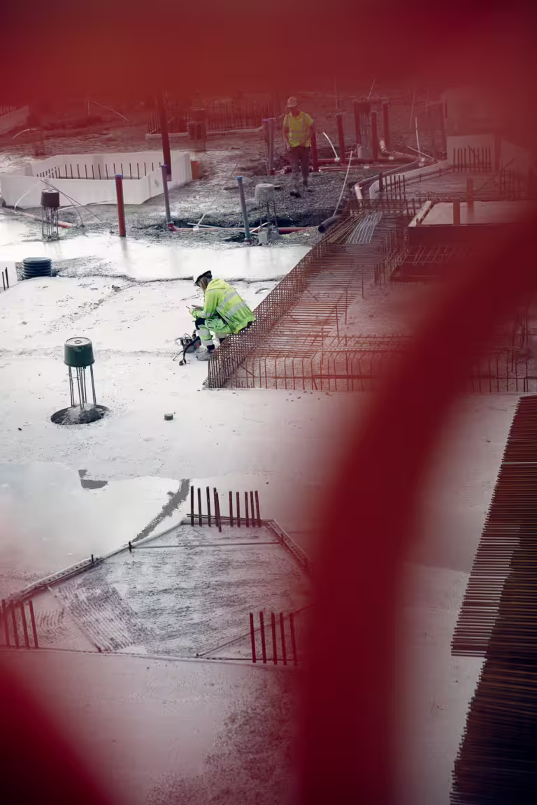 Bygningsarbeider sitter på byggeplass og bruker mobilapp.