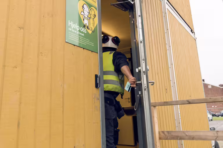 Bygningsarbeider går gjennom døren til byggbrakke.