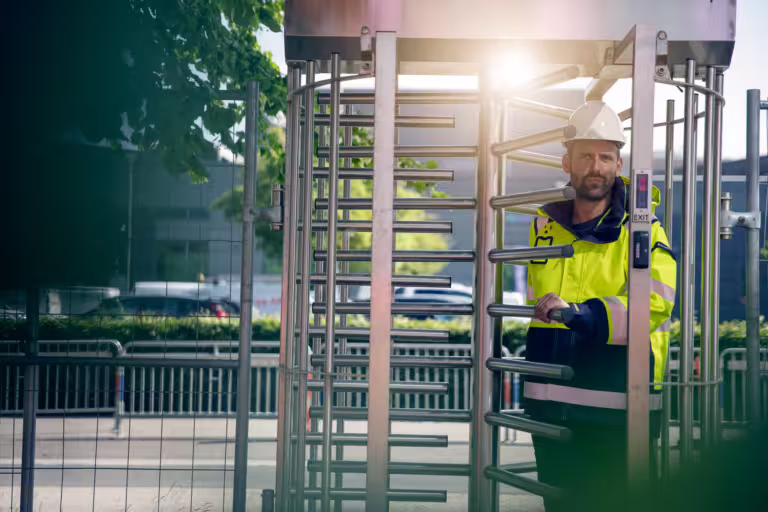 Hovedentreprenør passerer gjennom rotasjonsport med adgangskontroll på byggeplass.