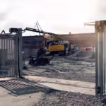 Kjøretøy passerer gjennom kjøreport ved byggeplass med digital adgangskontroll.