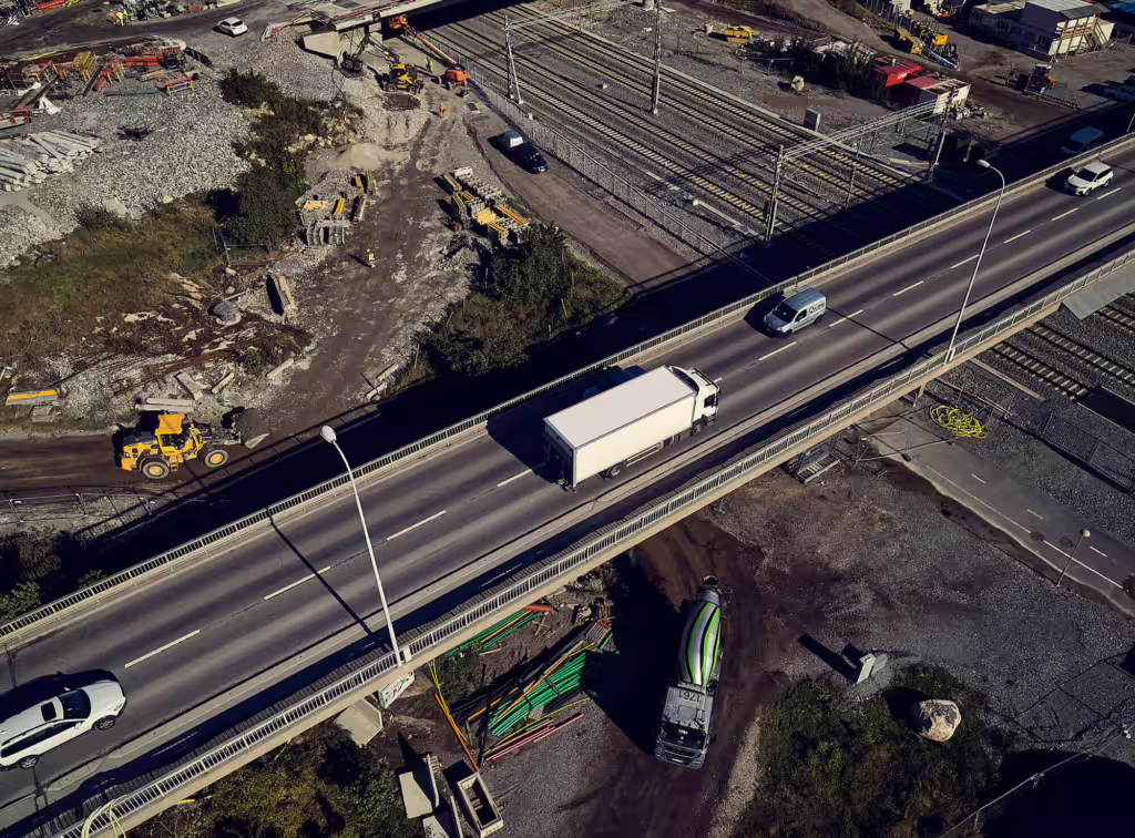 Lastbil kör över bro i industriområde, sedd från ovan