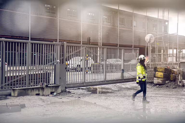 kvinna går igenom fordonsgrind på byggarbetsplats.