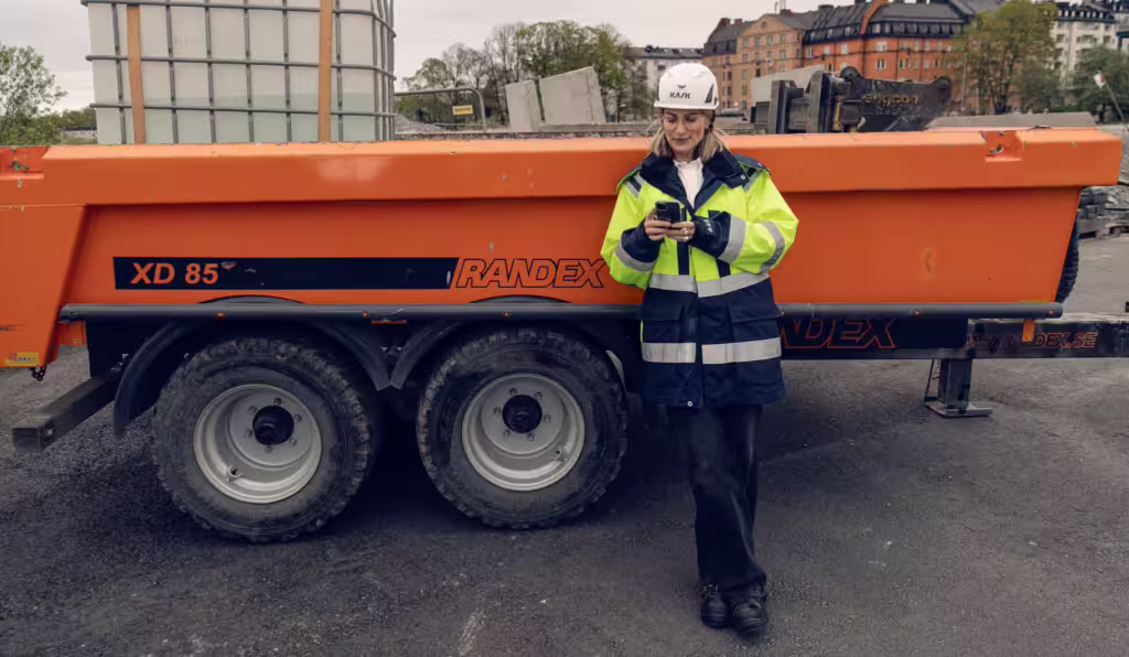 Kvinna med mobil på byggarbetsplats