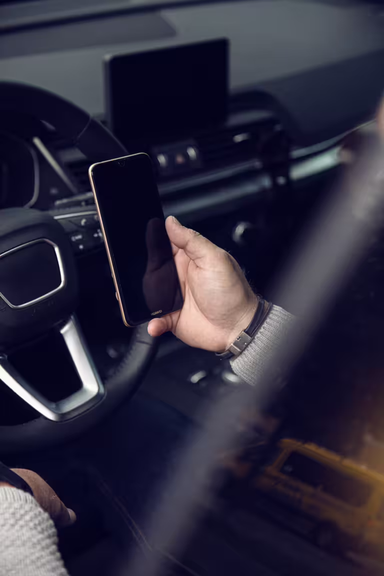 Hand med telefon som sköter milersättning via Infobric Fleet