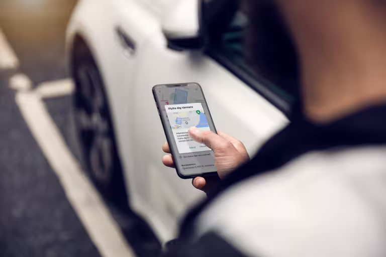 bil i bakgrunden och Ease CheckIn app i förgrunden som visar geofence