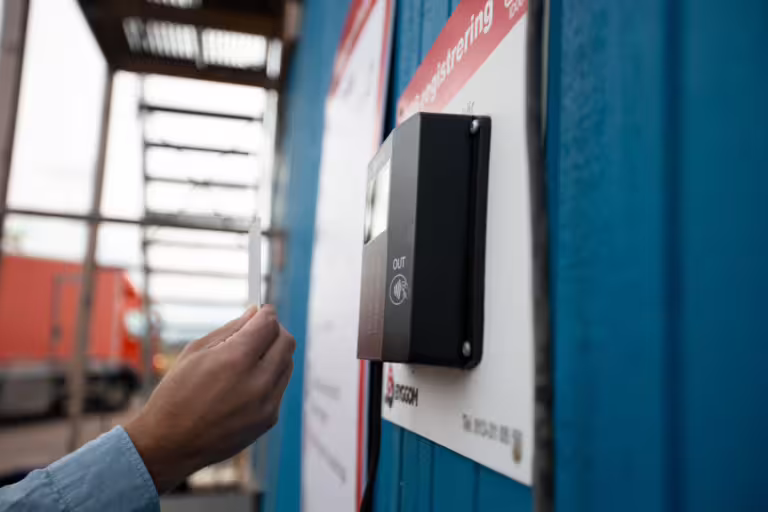 Person registrerar sig med ID06-kort på Regbox 250 vid byggarbetsplats.