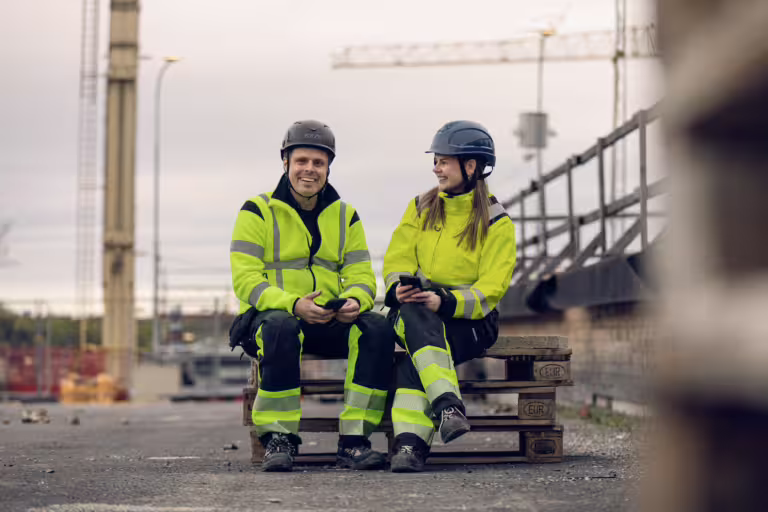 två byggarbetare på byggarbetsplats i varselkläder