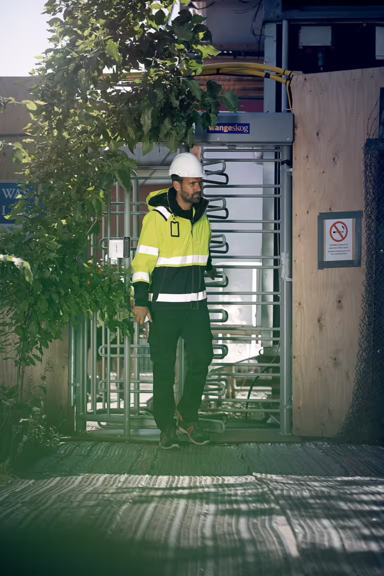 Person passerar genom rotationsgrind på byggarbetsplats med behörighetsstyrd inpassering.
