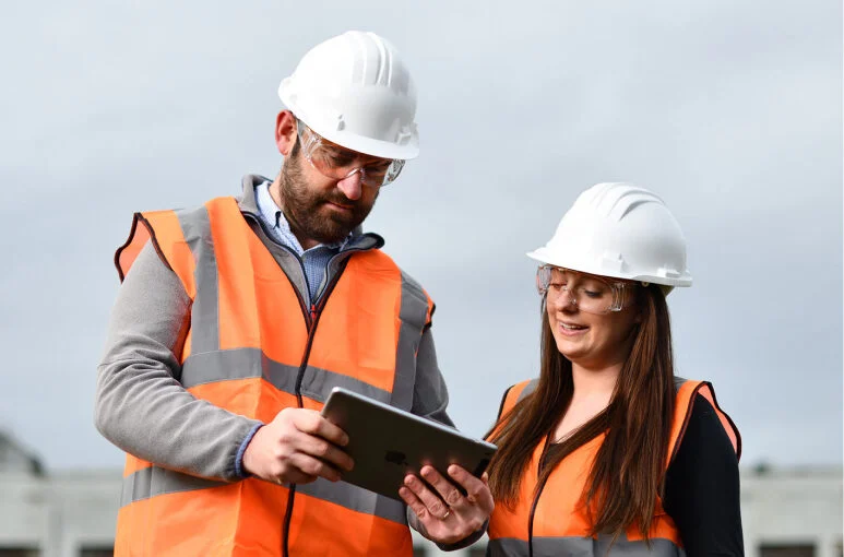 two construction workers looking at an ipad at msite dashboards