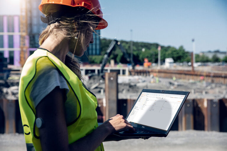 Woman at a construction site with a laptop working with Workforce Management